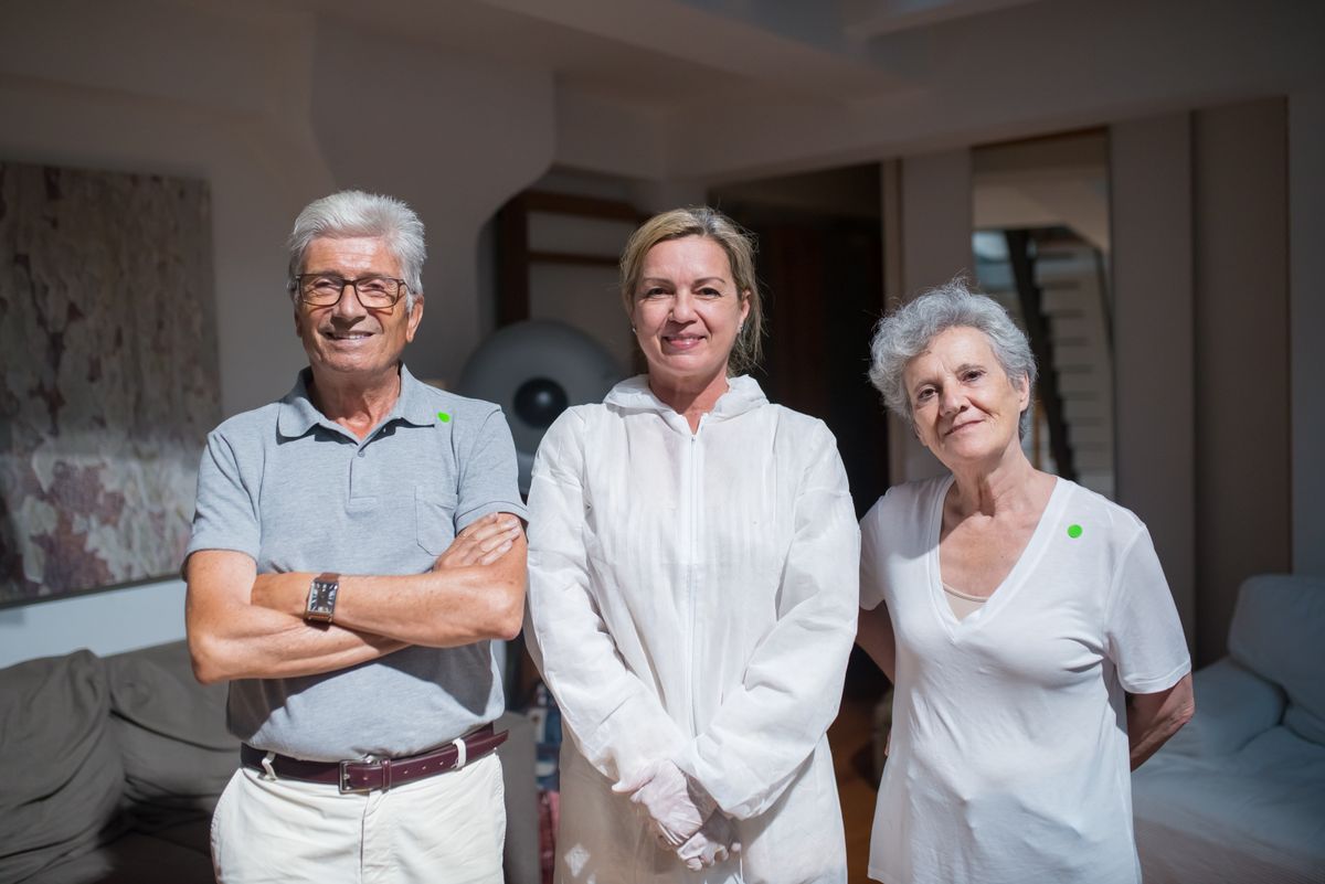 Caregiver standing with two smiling older adults at home